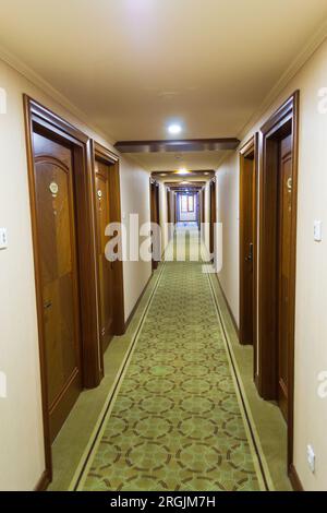 Langer Flur mit Zimmertüren und Teppich eines Hotels und Licht am Ende in Istanbul, Türkei Stockfoto