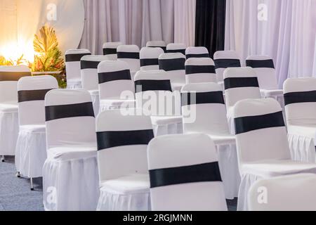 Einrichtung des Veranstaltungsorts für Hochzeitsempfänge im Innenbereich mit einer ordentlichen Anordnung von Tischen und Stühlen Stockfoto