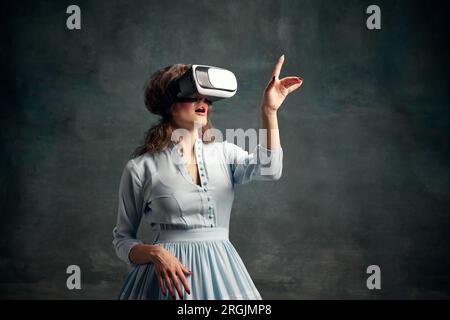 Porträt einer aristokratischen Frau mit blauem historischen Kleid und VR-Brille. Geräte. Königin der Technik. Stockfoto