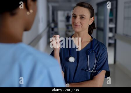 Verschiedene Ärztinnen tragen Kittel und diskutieren Arbeit im Flur des Krankenhauses Stockfoto