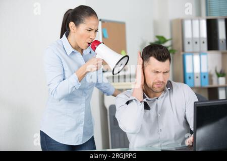 Eine Frau mit einem Megafon, die den Mann anschreit Stockfoto