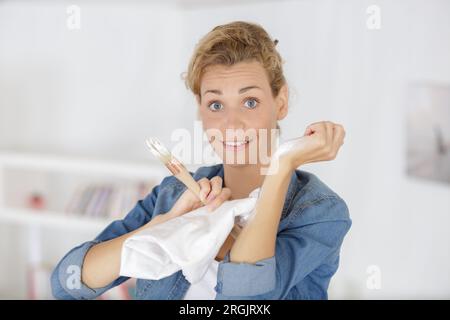 Eine Frau, die nach dem Dekorieren Farbe vom Arm reibt Stockfoto