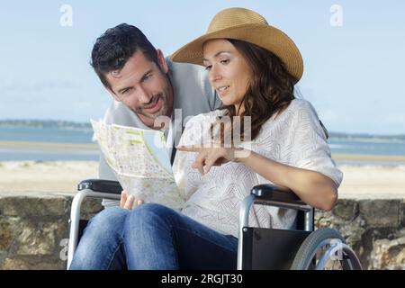 Behinderte Frau im Rollstuhl und Freund auf Urlaub Stockfoto