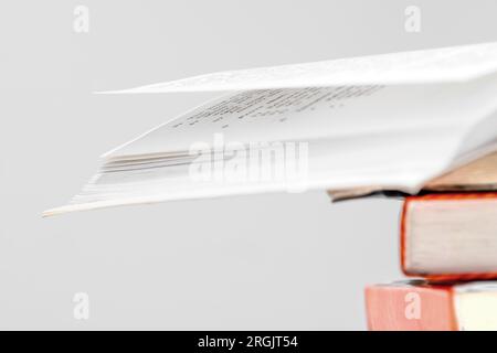 Ein Stapel Bücher in der Bibliothek, eines davon oben offen, mehrfarbige Buchrücken. Bildungskonzept. Stockfoto