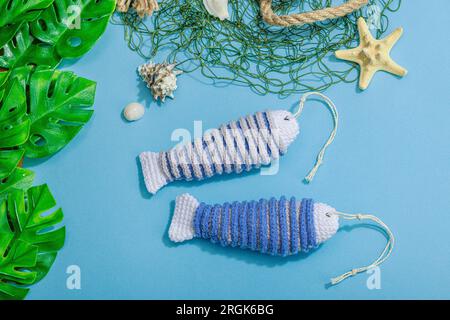 Handgefertigtes Marinekonzept. Gestrickte Sardinenfische im nautischen Stil. Fischernetz, traditionelle Einrichtung im Meer. Hartes Licht, dunkler Schatten, trendy blauer Hintergrund Stockfoto