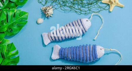 Handgefertigtes Marinekonzept. Gestrickte Sardinenfische im nautischen Stil. Fischernetz, traditionelle Einrichtung im Meer. Hartes Licht, dunkler Schatten, trendy blauer Hintergrund Stockfoto