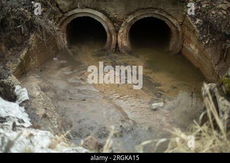 Rohre im Boden. Wasser ablassen. Industrieabfälle. Schacht unter der Straße. Stockfoto