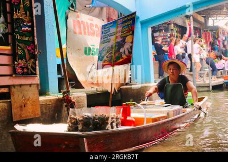 24. Dezember 2018, Bangkok, Thailand - Händler, die verschiedene Snacks, frittierte Speisen und andere Artikel auf den Booten in den belebten Kanälen von Damnoen Saduak verkaufen Stockfoto