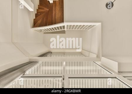 Das Innere eines Hauses mit weißen Wänden und hölzernen Treppen führt in die obere Etage, die aus Holz besteht Stockfoto