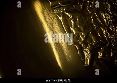 Goldene Textur. Plastikfolie. Goldene Welle. Hintergrund: Dunkelgelb. Stockfoto