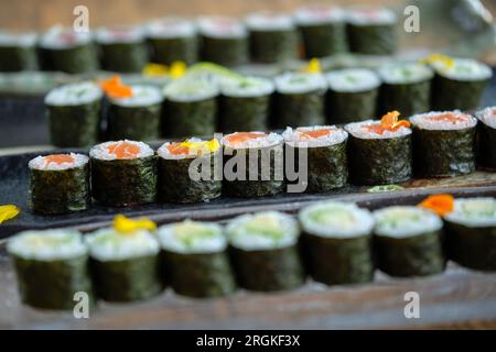 Marmortabletts mit Sushi-Brötchen mit Lachs auf einem Holztisch vor verschwommenem Hintergrund Stockfoto