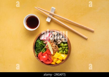 Von oben sehen Sie eine gesunde Lunch-Schüssel mit Rettich-Tofu-Mango-Tomaten mit Seetang-Salat und Edamame-Bohnen und knusprigen Zwiebeln in der Nähe von Essstäbchen und Sojabohnen Stockfoto