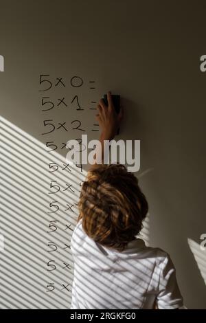 Rückansicht von nicht erkennbaren Schulkindern, die während des Unterrichts in der Schule Antworten auf mathematische Beispiele auf dem Whiteboard löschen Stockfoto