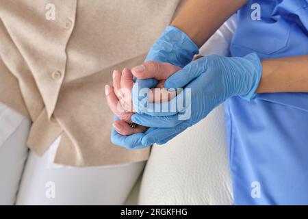 Von oben der Ernte nicht erkennbarer Arzt in Einweghandschuhen und Uniform halten Patienten von Hand während der Untersuchung Stockfoto