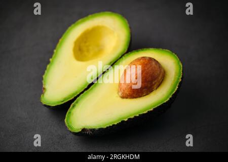 Stammfoto von halbfrischer grüner organischer Avocado isoliert auf schwarzem Hintergrund. Stockfoto