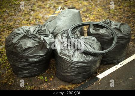 Müllsäcke auf der Straße. Schwarze Taschen. Reinigung im Hof. Plastikmüllbeutel. Stockfoto