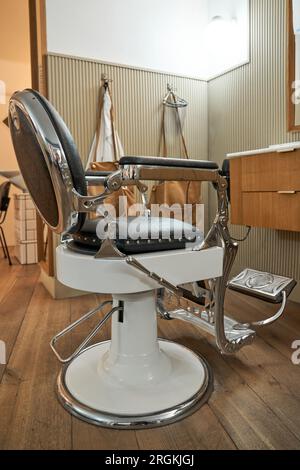 Komfortabler Ledersessel in einem modernen, hellen Friseursalon mit Holzfußboden und stilvoller Einrichtung Stockfoto