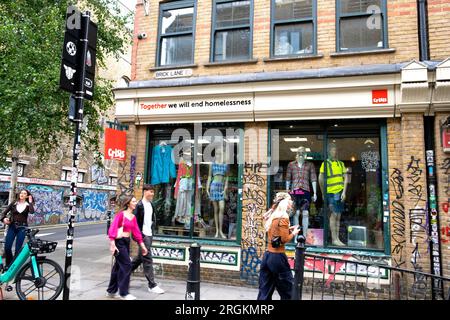 Brick Lane Retro-Bekleidungsshop CRISIS „Together we will end Obdachlosigkeit“-Schild auf der Außenfassade des Geschäfts Brick Lane East London UK KATHY DEWITT Stockfoto