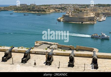 Valletta, Malta - 8. Juni 2023: Solider in traditioneller Uniform, der neben einer Reihe alter Kanonen in der Salut-Batterie an den Stadtmauern steht Stockfoto