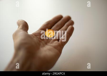 Russisches Geld in der Hand. Zehn Rubel in deiner Handfläche. Goldmünze. Kleines Einkommen. Stockfoto