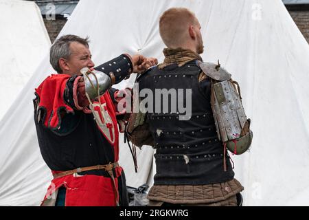 SHLISSELBURG, RUSSLAND - 29. JULI 2023: Squire fixiert Ritterpanzerung vor dem Kampf. Historisches Festival „Epic Island“. Die Festung Oreshek Stockfoto