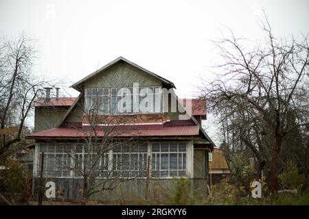 Ein altes Haus auf dem Land. Großes Fenster im Holzhaus. Gebäude aus Brettern. Stockfoto