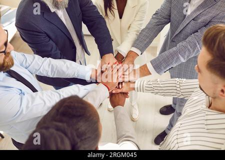 Ein Team aus multiethnischen jungen und leitenden Geschäftsleuten, die sich zusammenhalten Stockfoto
