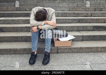 Der unglückliche Manager wurde von seinem Job gefeuert. Ein trauriger Arbeiter sitzt auf den Stufen eines Business Centers, nachdem er entlassen wurde, Krise, Depression. Stockfoto