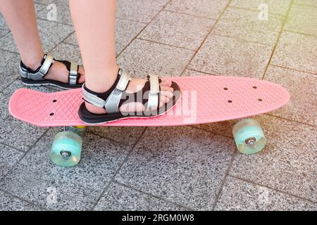 Nahaufnahme von Kinderfüßen, die auf einem Skateboard stehen. Lifestyle Stockfoto