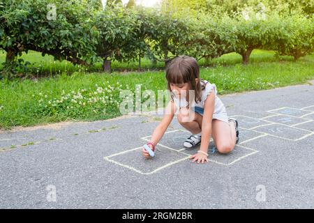 Das kleine Mädchen malt mit Kreide auf dem Bürgersteig im Park Stockfoto