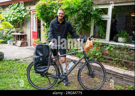 Oud Gastel, Nordbrabant, Niederlande, 03 2023. Juli - 44 Yo man mit Trekkingrad steht in einem alten Haus mit grüner Dekoration Stockfoto