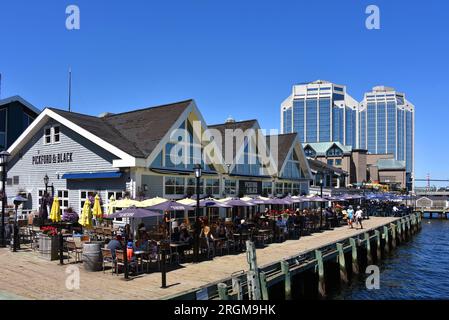 Halifax, Kanada - 2. August 2023: Gäste essen auf der Terrasse von Pitchford and Black, einem Restaurant an der Halifax Waterfront, das eine Touristenattraktion ist Stockfoto