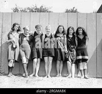 Junge Frauen, die Badeanzüge tragen und an einem Zaun entlang stehen. 1920 Stockfoto