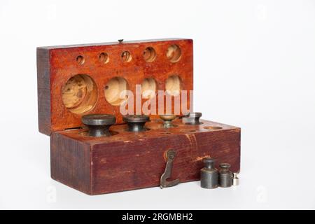 Alte rostige Gewichte für Waagen verschiedener Größen und Waagen in einer Holzkiste auf weißem Hintergrund Stockfoto
