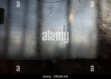 Zerkratzte Oberfläche. Kratzer auf Glas. Transparente Textur in kleinen Strichen. Unscharfer Hintergrund außerhalb des Fensters. Stockfoto
