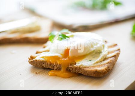 Gebratenes Toastbrot mit Brotaufstrich und pochiertem Ei auf einem Holztisch. Schnelles Frühstück. Stockfoto