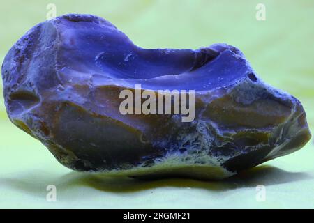 Nahaufnahme, Makro, ein isolierter Stein, der an einem Strand gefunden wurde. Raue und glatte Oberfläche. Grau, schwarz, dunkelblau, braun, grün. Stockfoto