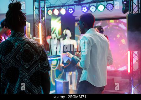 Die Menge feiert auf der Tanzfläche und genießt das Nachtleben im dunklen Club mit Scheinwerfern. Verschiedene Leute tanzten und hatten Spaß, während sie in Clubs gingen und Dikotheken im Nachtclub besuchten Stockfoto