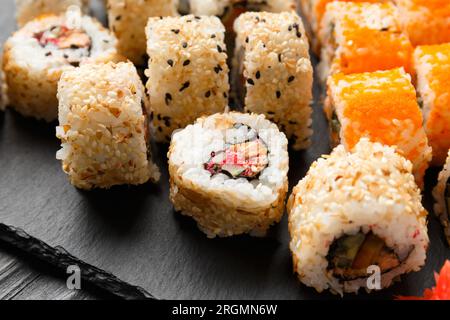 Lachsrollen auf dunklem Hintergrund. Rotes Sushi mit Sesam auf schwarzem Hintergrund Stockfoto