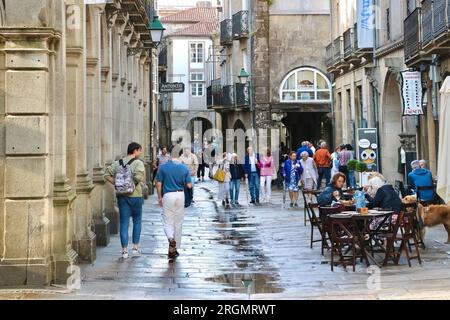 Touristen an einem nassen Juni-Tag in einer engen Fußgängerzone mit Café-Terrasse Santiago de Compostela Galicia Spanien Stockfoto