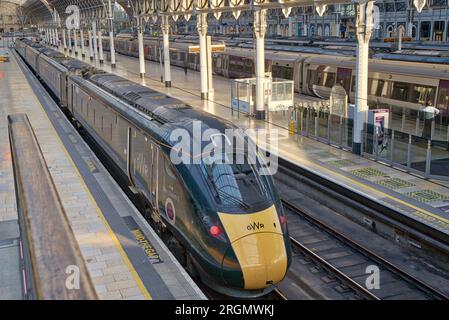 Blick von vorne nach hinten auf den GWR-Zug, der bei Abendsonne scheint, auf den Bahnsteig Paddington Station, der Pendlerpassagiere von London UK nach Hause bringt Stockfoto