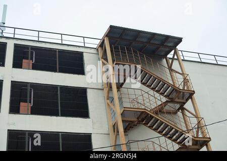 Treppen vor dem Gebäude. Feuerleiter an der Wand. Gebäude vom Innenhof. Verstärkung. Stockfoto