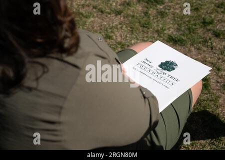 Bericht: USDA-Besuch in Newark, New Jersey, um den Preis für die Baumpflanzung bekannt zu geben (April 2023) - Frau, die Dr. Homer Wilkes mit einer Broschüre von der New Jersey Tree Foundation zuhört Stockfoto