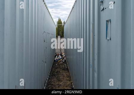 Schrott, der sich zwischen zwei Metall- und Containergebäuden angesammelt hat Stockfoto
