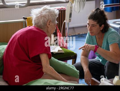 Berlin, Deutschland. 31. Juli 2023. Pflegekraft Ramona Rössner spricht während eines Hausbesuchs mit ihrer Patientin, der 97-jährigen Senior Brigitte Richter, die Pflege benötigt. Kredit: Monika Skolimowska/dpa/Alamy Live News Stockfoto