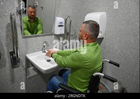 Nicht exklusiv: LEMBERG, UKRAINE - 9. AUGUST 2023 - ein Unternehmer wäscht sich die Hände in einer zugänglichen Toilette, während Geschäftsleute die Superhumans umfahren Stockfoto