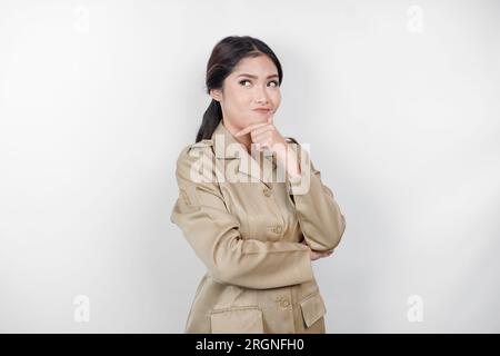 Verwirrte asiatische Regierungsarbeiterinnen haben Denkgesten. PNS trägt eine khakifarbene Uniform. Stockfoto