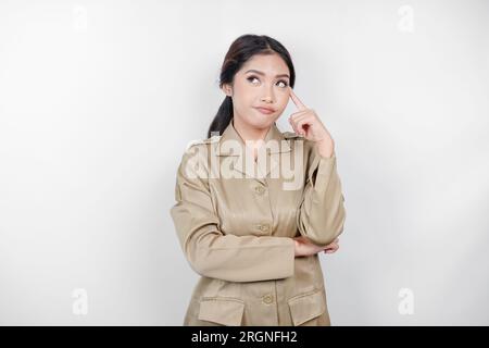 Verwirrte asiatische Regierungsarbeiterinnen haben Denkgesten. PNS trägt eine khakifarbene Uniform. Stockfoto