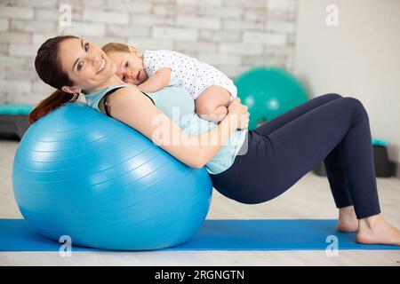 Sportliche Mutter macht Pilates e mit ihrem Baby Stockfoto