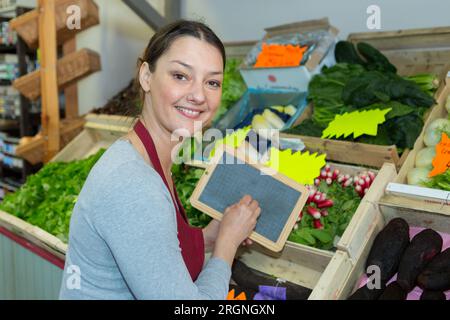 Weibliche Angestellte mit einem Schild im Supermarkt Stockfoto